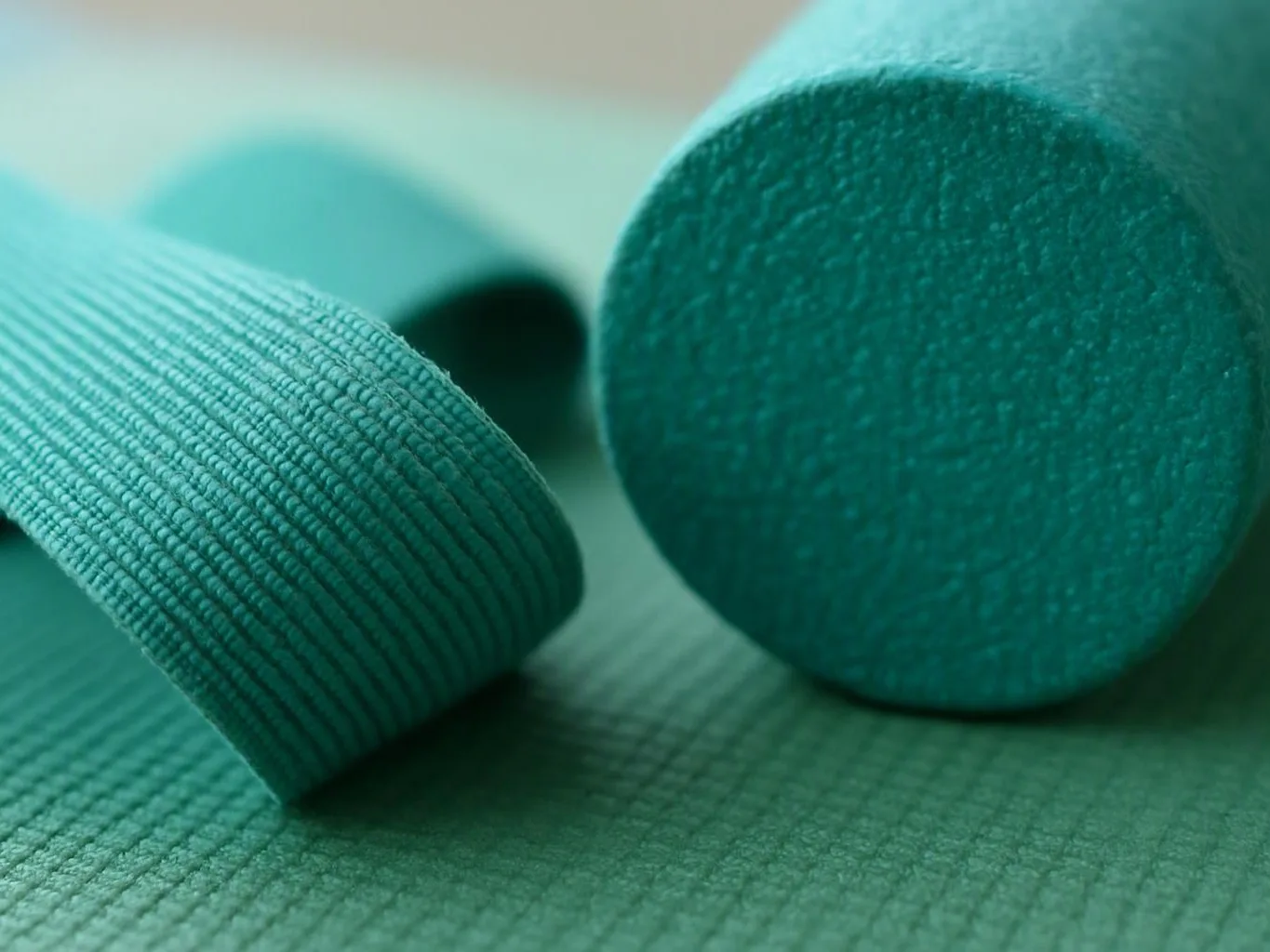 Close-up of teal textured fabric rolls and a round fabric end on a flat surface